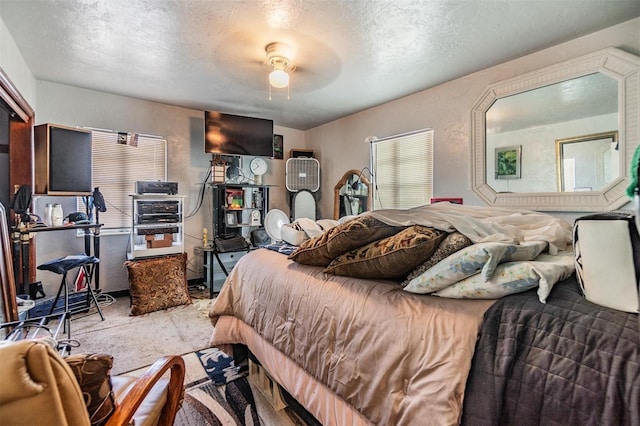 bedroom featuring ceiling fan, light carpet, and a textured ceiling