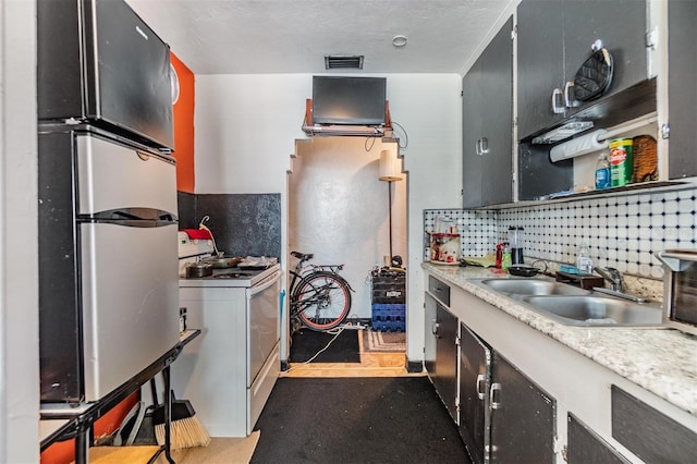 kitchen with stainless steel refrigerator, white electric stove, sink, decorative backsplash, and a textured ceiling