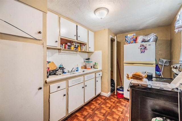 kitchen with white refrigerator, white cabinets, dark parquet floors, and decorative backsplash