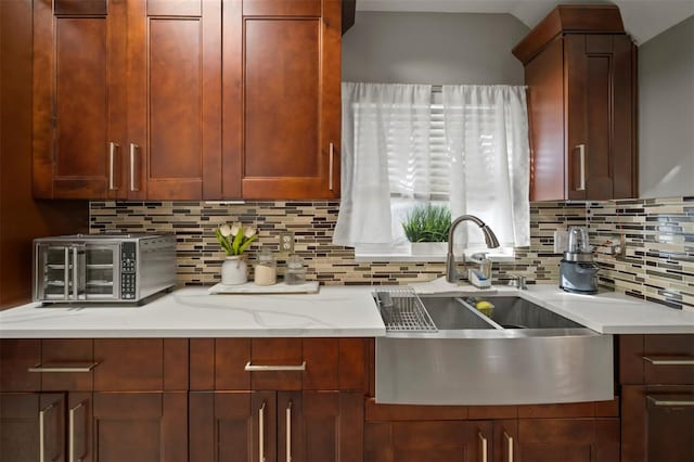 kitchen featuring light stone countertops, sink, and backsplash