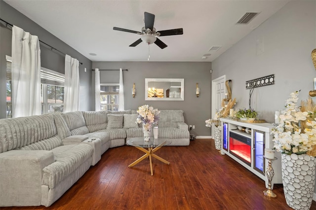 living room featuring a fireplace, dark wood-type flooring, and ceiling fan