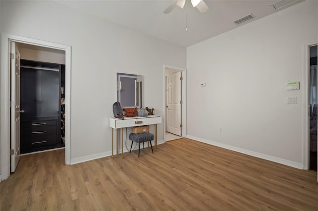 bedroom with ceiling fan, a walk in closet, light wood-type flooring, and a closet