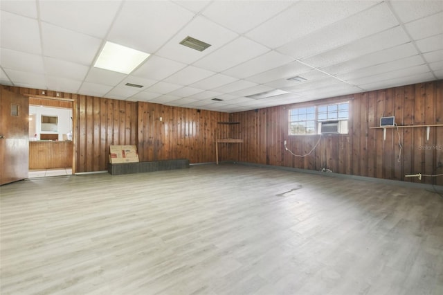 spare room with wood-type flooring, a paneled ceiling, and wood walls