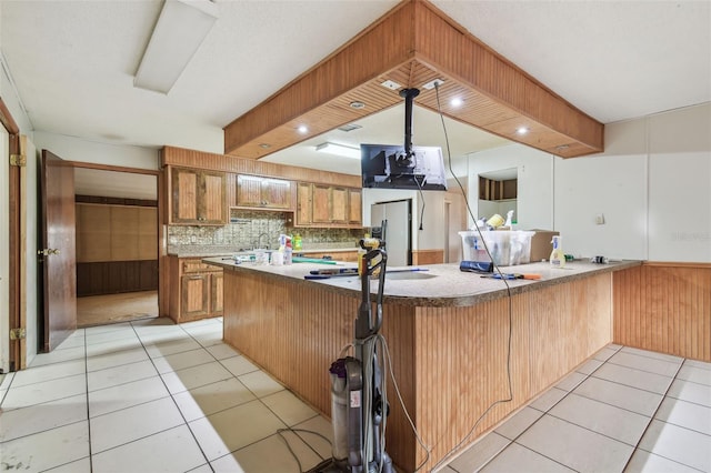 kitchen featuring light tile patterned flooring, stainless steel fridge, and kitchen peninsula