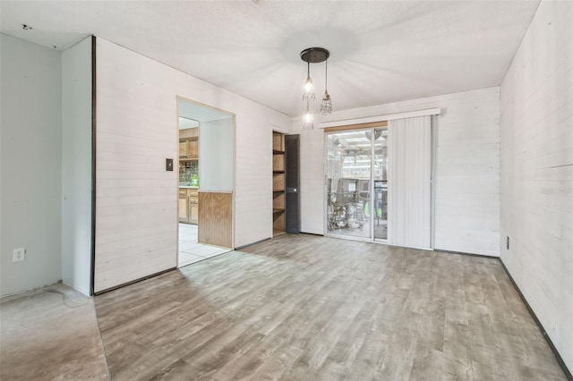 empty room featuring a textured ceiling and light hardwood / wood-style flooring