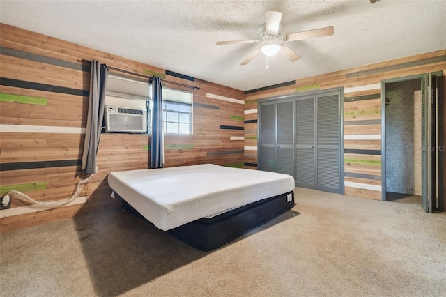 carpeted bedroom with cooling unit, ceiling fan, wooden walls, and a textured ceiling