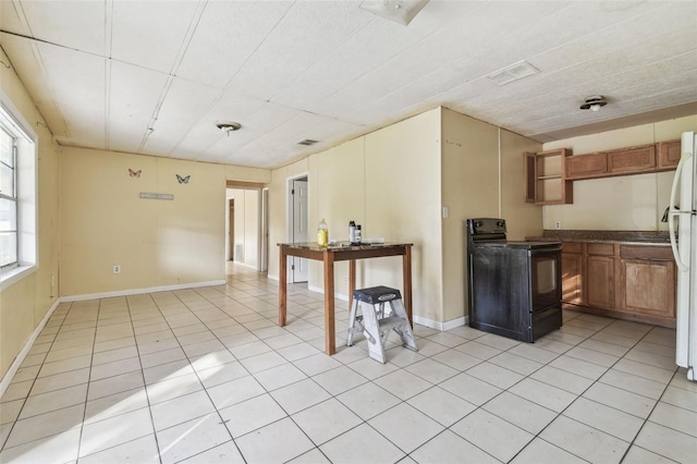 kitchen featuring white refrigerator, black electric range oven, and light tile patterned floors