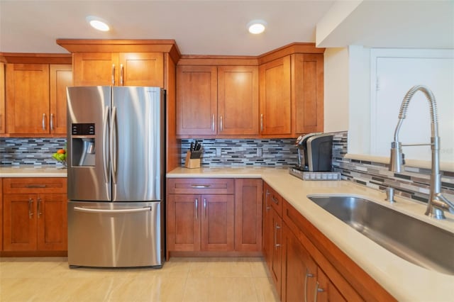 kitchen featuring stainless steel fridge with ice dispenser, backsplash, sink, and light tile patterned flooring