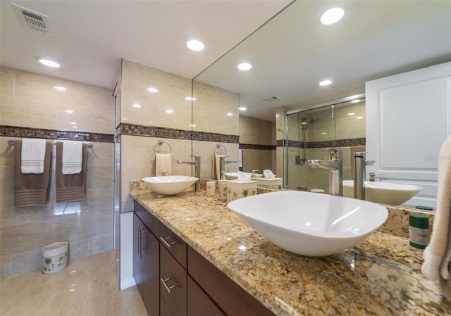 bathroom with vanity, an enclosed shower, and tile walls