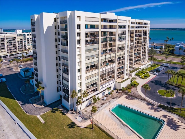 view of building exterior featuring a water view and a community pool