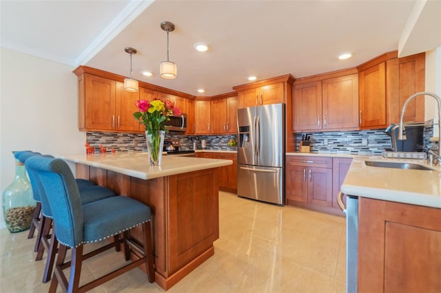 kitchen with a kitchen bar, sink, decorative light fixtures, kitchen peninsula, and stainless steel appliances