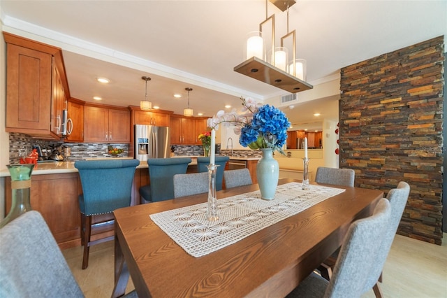 dining space with crown molding and sink