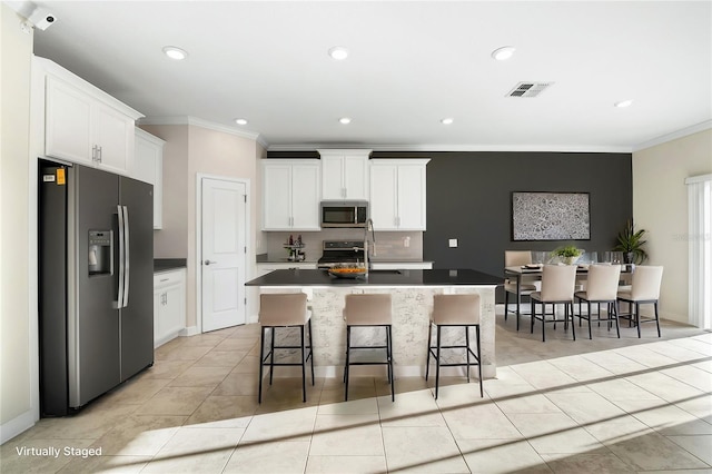 kitchen featuring a breakfast bar area, white cabinets, light tile patterned floors, stainless steel appliances, and a center island with sink