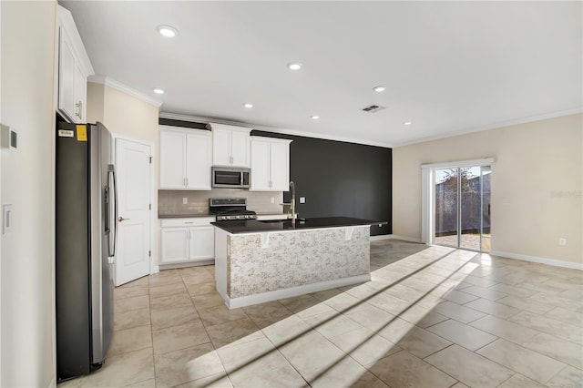 kitchen featuring appliances with stainless steel finishes, tasteful backsplash, white cabinets, crown molding, and a center island with sink