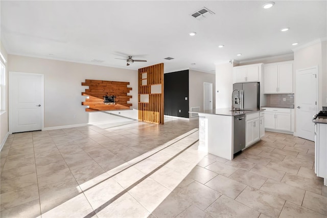 kitchen featuring ornamental molding, appliances with stainless steel finishes, an island with sink, ceiling fan, and white cabinets