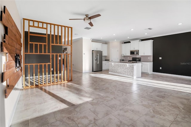 kitchen with sink, white cabinets, a kitchen island with sink, stainless steel appliances, and crown molding