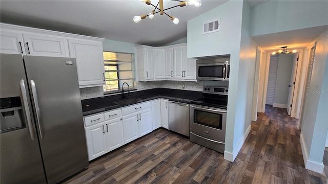 kitchen featuring appliances with stainless steel finishes, tasteful backsplash, white cabinetry, sink, and a notable chandelier