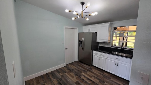 kitchen with white cabinetry, stainless steel fridge, sink, and vaulted ceiling