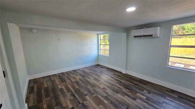 empty room featuring dark hardwood / wood-style floors, an AC wall unit, and a textured ceiling