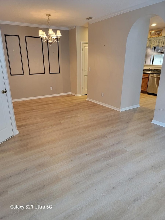 spare room with a notable chandelier, crown molding, and light hardwood / wood-style flooring