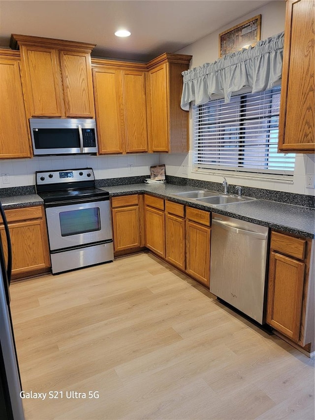 kitchen featuring tasteful backsplash, appliances with stainless steel finishes, sink, and light hardwood / wood-style flooring