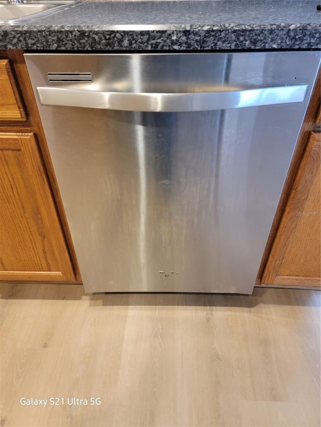 details with dark stone counters, sink, and light hardwood / wood-style floors