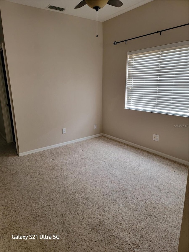 empty room featuring ceiling fan and carpet