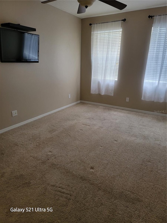 carpeted spare room featuring ceiling fan