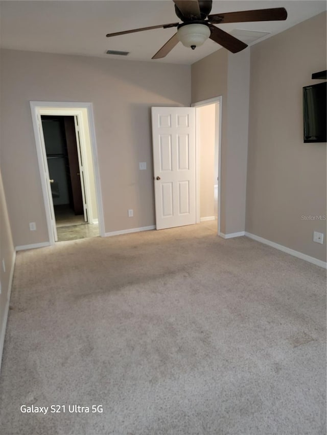 unfurnished bedroom with ceiling fan, light colored carpet, and ensuite bath