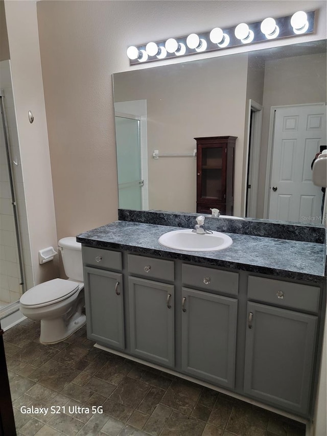 bathroom featuring vanity, a shower with door, and toilet