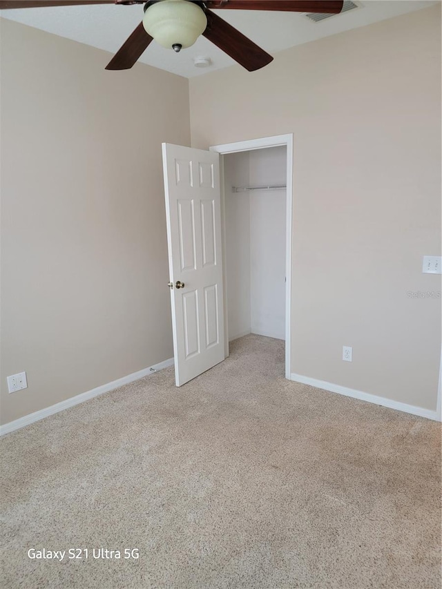 unfurnished bedroom with ceiling fan, light carpet, and a closet