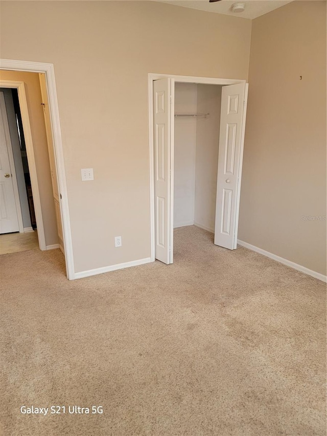 unfurnished bedroom featuring light colored carpet and a closet