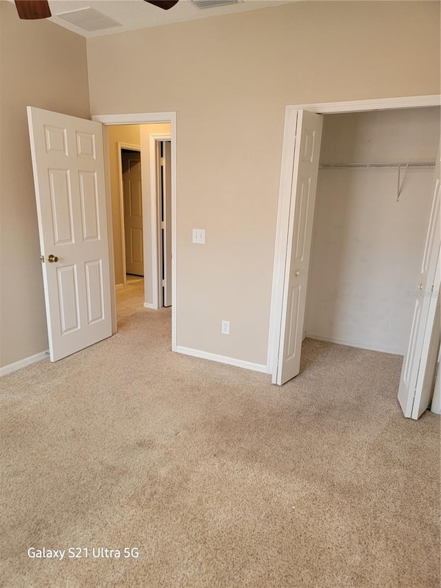 unfurnished bedroom with ceiling fan, light colored carpet, and a closet