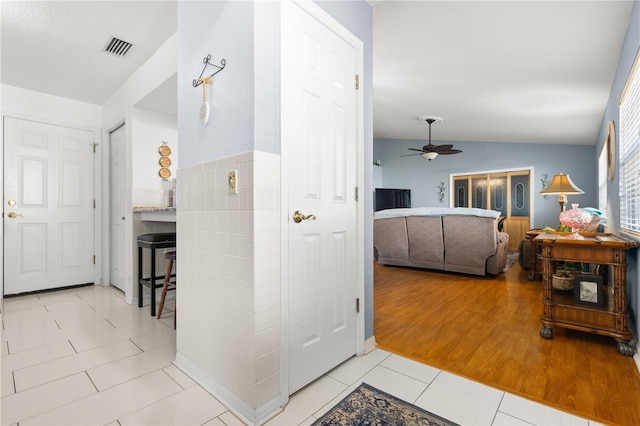 hall with lofted ceiling and light tile patterned flooring