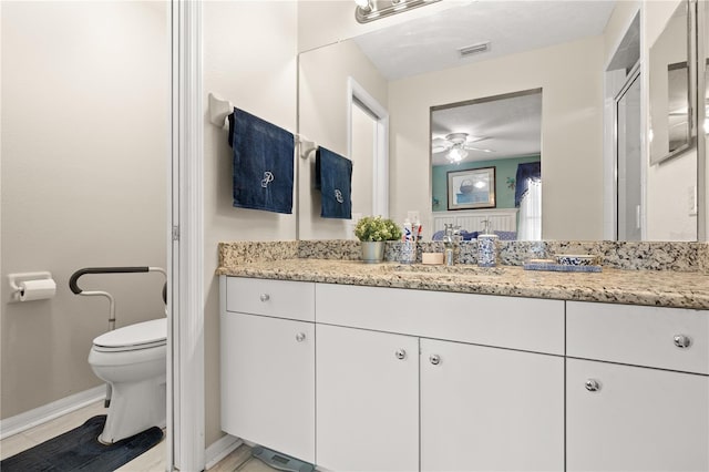 bathroom featuring vanity, ceiling fan, a shower with shower door, and toilet