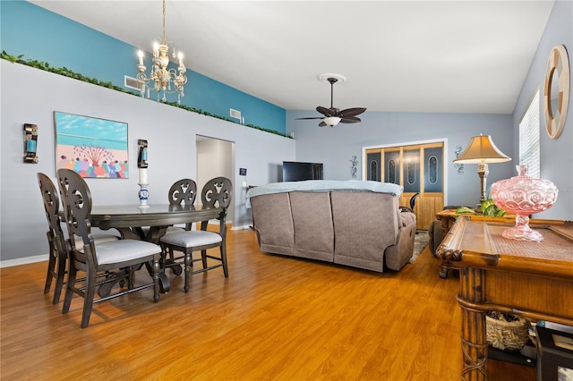 dining space featuring ceiling fan with notable chandelier, hardwood / wood-style floors, and lofted ceiling