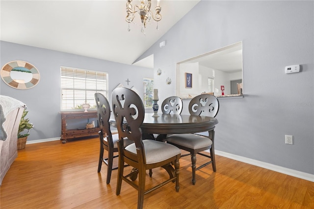 dining space featuring high vaulted ceiling, a chandelier, and light hardwood / wood-style floors