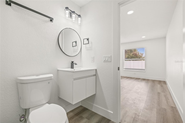 bathroom with vanity, toilet, and hardwood / wood-style floors