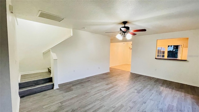 unfurnished living room featuring hardwood / wood-style flooring, ceiling fan, and a textured ceiling