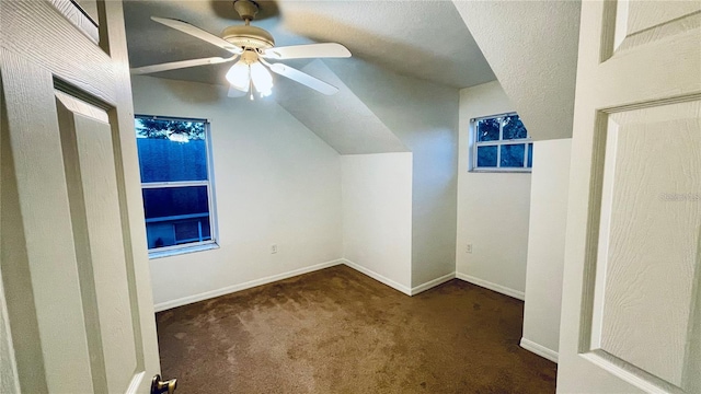 bonus room featuring dark carpet, vaulted ceiling, a textured ceiling, and ceiling fan