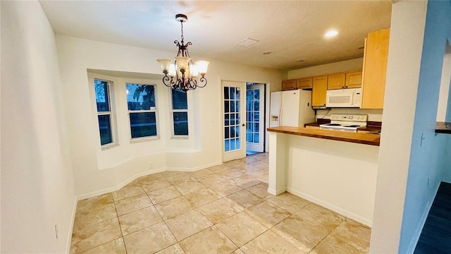 kitchen featuring decorative light fixtures, white appliances, kitchen peninsula, an inviting chandelier, and french doors