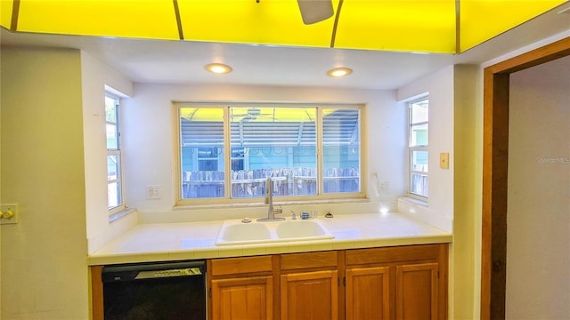 kitchen with a healthy amount of sunlight, tile counters, dishwasher, and sink