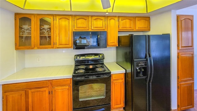 kitchen with backsplash, tile counters, and black appliances