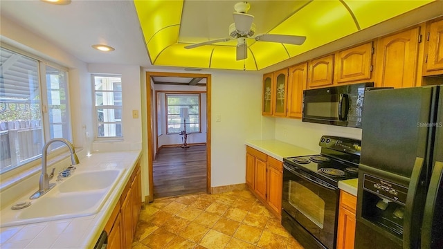 kitchen featuring sink, a tray ceiling, black appliances, and ceiling fan