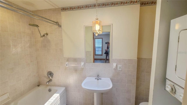 bathroom featuring tiled shower / bath, stacked washer / drying machine, and tile walls