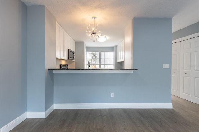 kitchen featuring a notable chandelier, kitchen peninsula, hanging light fixtures, and white cabinets