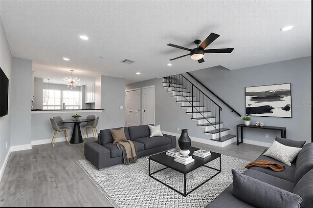 living room with sink, ceiling fan with notable chandelier, wood-type flooring, and a textured ceiling