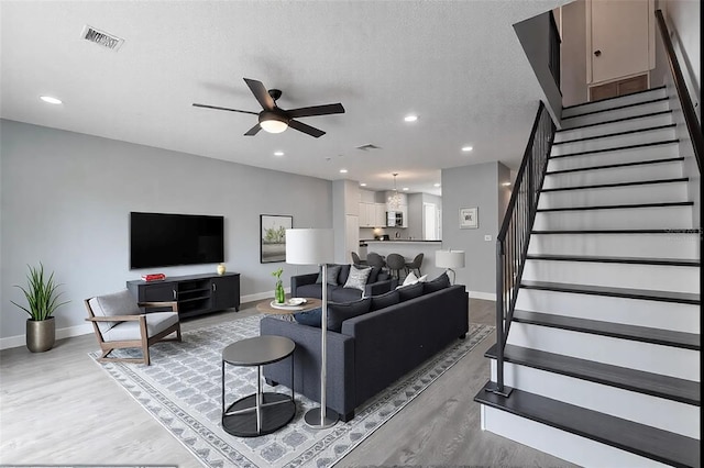 living room with ceiling fan, hardwood / wood-style flooring, and a textured ceiling