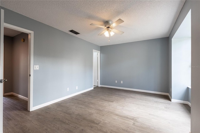 unfurnished room featuring dark wood-type flooring, ceiling fan, and a textured ceiling