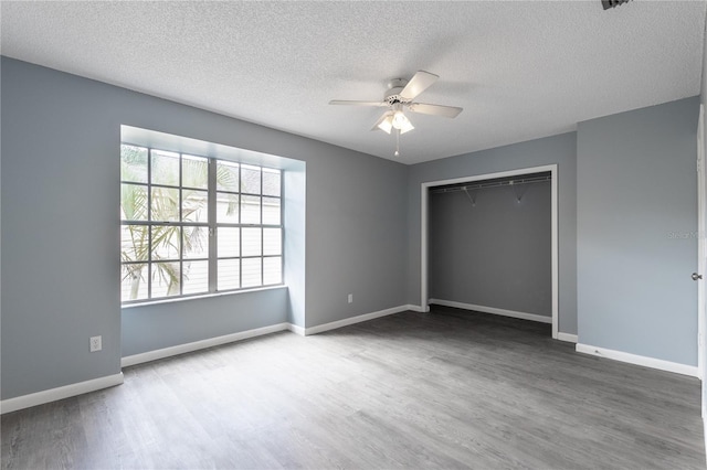 unfurnished bedroom featuring hardwood / wood-style flooring, ceiling fan, a textured ceiling, and a closet